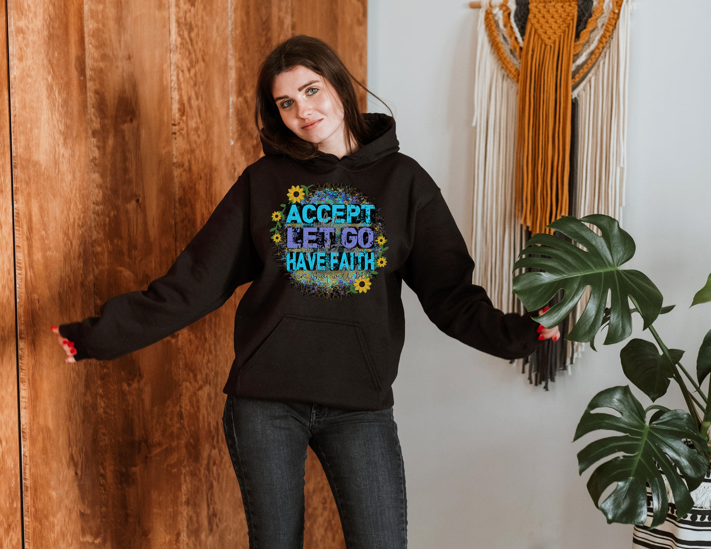 Woman posing in a black hoodie with a bright blue graphic print